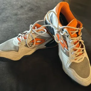Lotto men’s sneaker tennis shoes in white with bright orange accents